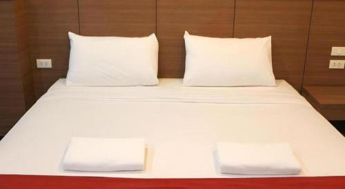 a large white bed with two pillows on it at The Grace Residence in Surin