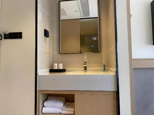 une salle de bain avec un lavabo, un miroir et des serviettes dans l'établissement City Comfort Inn Wuhan Yangluo Wanda Plaza, à Wuhan