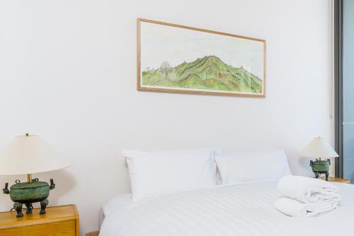 a bedroom with a white bed with a picture on the wall at Retro Gallery Escape in the Heart of Braddon - Hosted by Canstay in Braddon