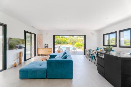 un salon avec un canapé bleu et une cuisine dans l'établissement Villa Hedone - Presqu'île de Giens Piscine Vue mer, à Hyères