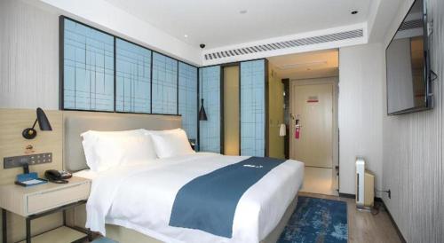 a bedroom with a large white bed and a desk at Echarm Hotel Shenzhen World Exhibition and Convention Center in Shenzhen