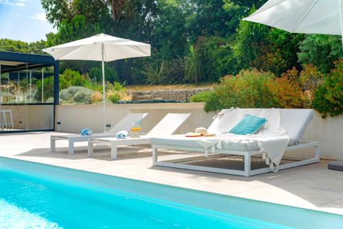- deux chaises longues et un parasol à côté de la piscine dans l'établissement Villa Hedone - Presqu'île de Giens Piscine Vue mer, à Hyères