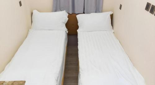 two beds in a room with white sheets at Metroplace Boutique in Hong Kong