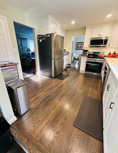 a kitchen with a stainless steel refrigerator and wooden floors at The Peaceful Perch Retreat Near NYC Elle's Home in Trenton