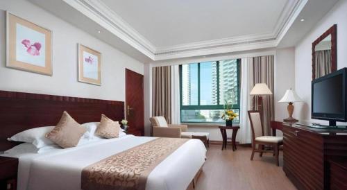 a hotel room with a bed and a television at Sanya Baohong Hotel in Sanya