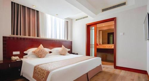 a bedroom with a large white bed and a mirror at Sanya Baohong Hotel in Sanya