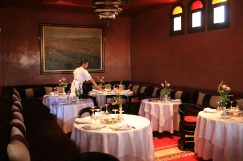 a woman standing in a dining room with tables at Al Fassia Aguedal in Marrakesh