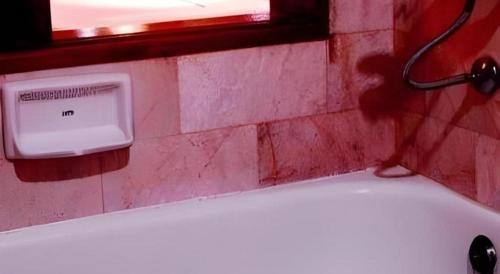 a bath tub in a bathroom with a window and a soap dispenser at Pailyn Hotel in Sukhothai