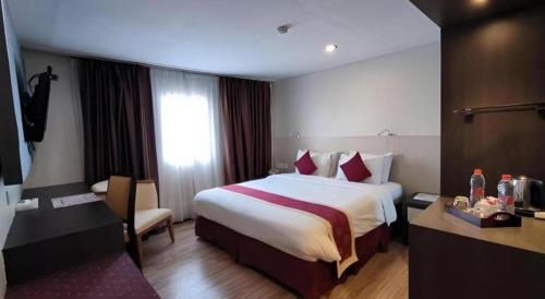 a hotel room with a bed and a desk at Hermes Palace Hotel Medan in Medan