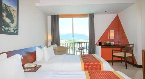 a hotel room with a large bed and a desk at Grand Surya Hotel Kediri in Kediri