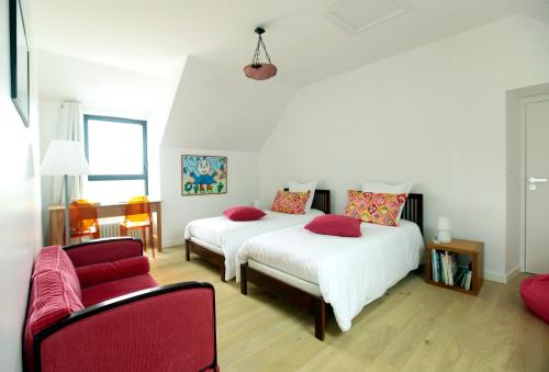 a bedroom with two beds and a red couch at Les Chambres d'hôtes de Kérasquer in Lannilis