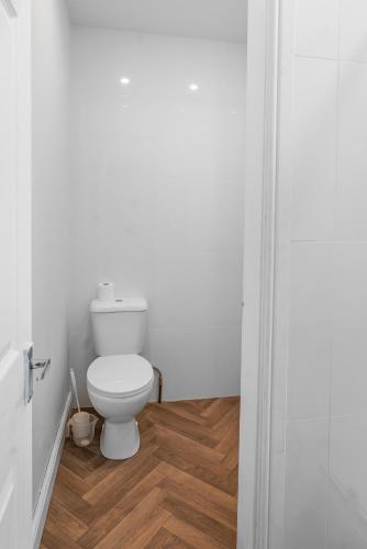 a bathroom with a toilet and a wooden floor at Unique 3 Bedrooms, 3 Ensuite, FREE WiFi, Private Parking in Tottington