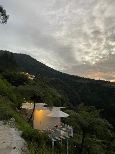 a white building with an umbrella on a hill at Glamping Visit Telaga Menjer in Garung