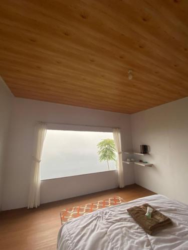 a bedroom with a bed and a large window at Glamping Visit Telaga Menjer in Garung