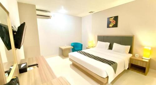 a hotel room with a bed and a tv at Orchardz Hotel Gajah Mada in Pontianak