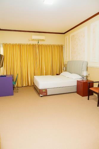 a bedroom with a large bed and a chair at Hotel Madiyara in Mukomuko