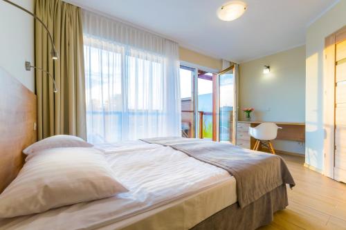 a bedroom with a large bed with a large window at Domki Apartamentowe Bueno in Dąbki