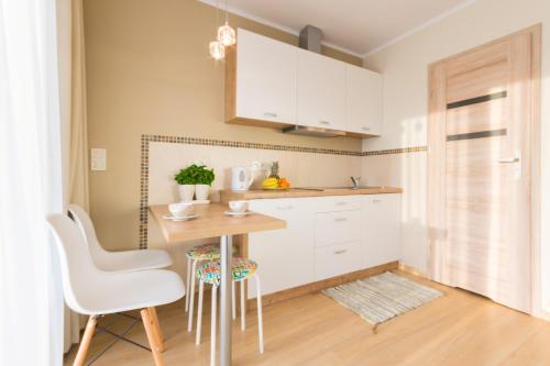 a kitchen with white cabinets and a table and chairs at Domki Apartamentowe Bueno in Dąbki