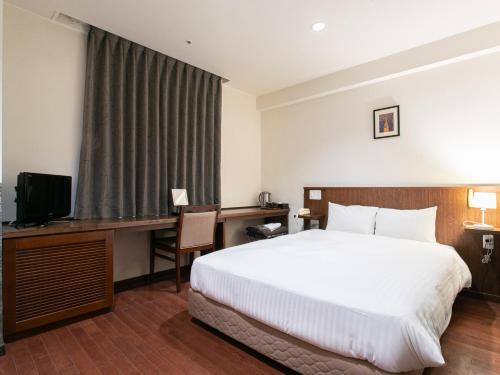 a hotel room with a bed and a desk and a television at Sutton Hotel Hakata City in Fukuoka