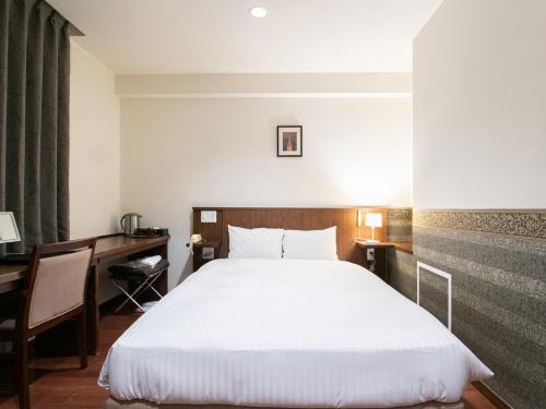 a hotel room with a bed and a desk at Sutton Hotel Hakata City in Fukuoka