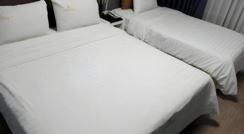 two beds in a hotel room with white sheets at BENIKEA Technovalley Hotel in Daejeon