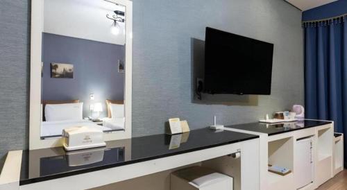 a hotel room with a television and a desk with a phone at BENIKEA Technovalley Hotel in Daejeon