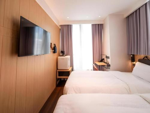 a hotel room with two beds and a flat screen tv at Harbour Bay Hotel in Hong Kong