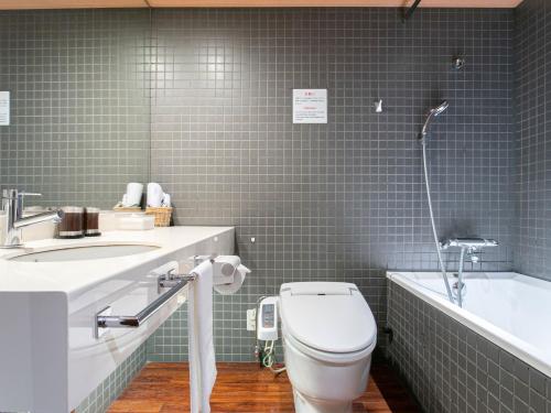 a bathroom with a toilet and a sink and a tub at Sutton Hotel Hakata City in Fukuoka