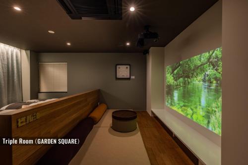 a room with a bed and a large tv on the wall at ビル泊 -Birupaku Decentralized Hotel- in Shizuoka