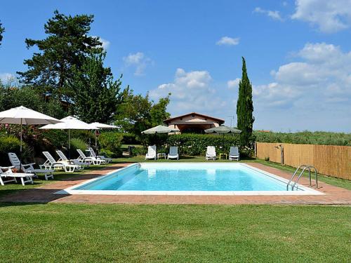 a swimming pool with chairs and umbrellas in a yard at Agriturismo Il Poggetto in San Gimignano