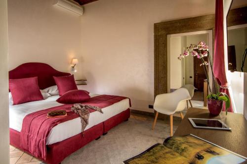 Schlafzimmer mit einem Bett mit roten Kissen und einem Tisch in der Unterkunft Palazzo Medusa in Rom