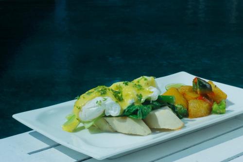 a white plate of food with vegetables and eggs at The Trawangan Resort in Gili Trawangan