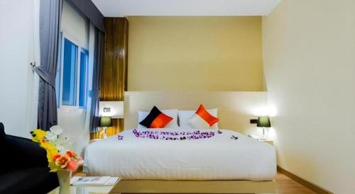a bedroom with a large white bed with purple pillows at GT Residence Hotel in Buriram