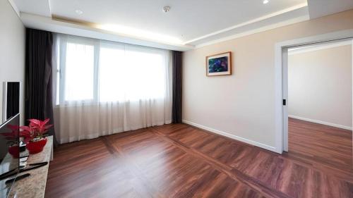 an empty living room with a large window and wooden floors at Galaxy Hotel in Jeju