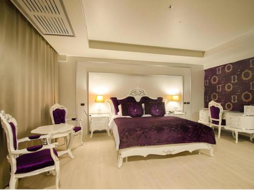 a bedroom with a bed and chairs and a table at Alvarez Hotel in Buriram