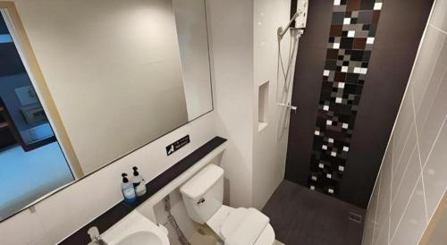 a bathroom with a toilet and a sink and a mirror at Wsotel Hotel in Songkhla