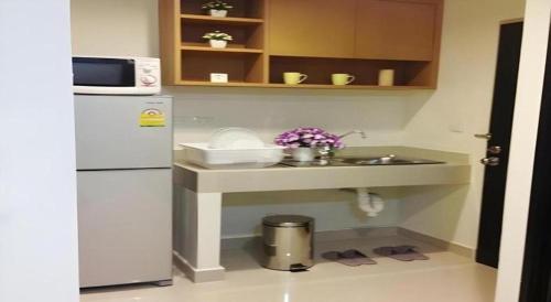 a small kitchen with a sink and a refrigerator at Ipremium Sukhumvit 81 Hotel in Bangkok