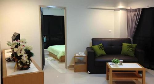 a living room with a couch and a bedroom at Ipremium Sukhumvit 81 Hotel in Bangkok