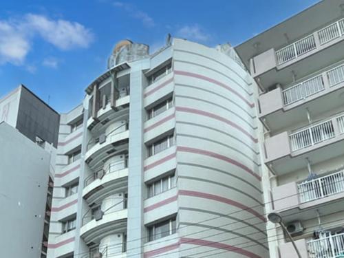 a white building with red and white stripes on it at Hotel LiVEMAX Naha Naminoue 1 in Naha