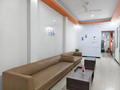 a living room with a brown couch and a table at YUTAKA INN Nabila Juanda Airport Sidoarjo in Semampir
