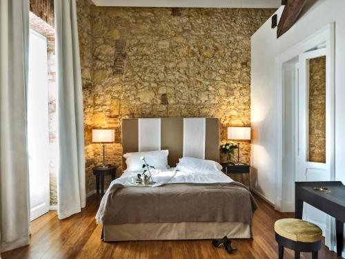 - une chambre avec un lit et un mur en pierre dans l'établissement Hotel Villa Fanny, à Cagliari