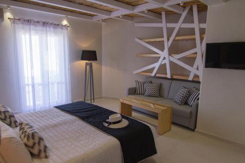 a bedroom with a bed and a couch and a tv at Avanti in Ios Chora