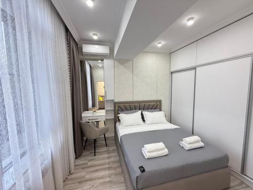 a bedroom with a bed and a desk with a chair at NOVA apartment BayTash Tower near TSUM and GUM in Bishkek