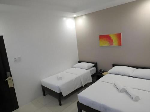a room with three beds and a painting on the wall at Fiesole Residence Inn in Dumaguete
