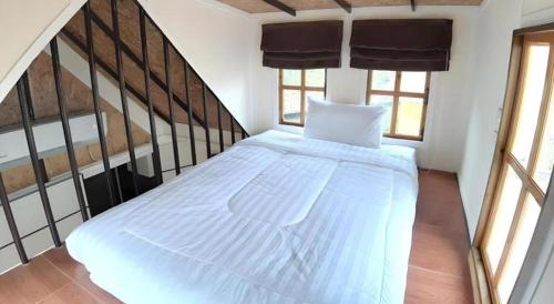 a white bed in a room with windows at Chang Puak Resort Damnoen Saduak in Ratchaburi