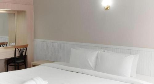 a bedroom with a white bed with a desk and a mirror at Merlin Hotel in Sungai Kolok