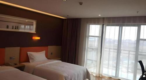 a hotel room with two beds and a large window at 7 Days Premium Nanjing Gaochun Beiling Road Branch in Gaochun