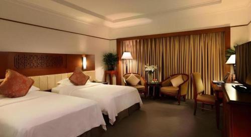 a hotel room with two beds and a desk at Capital Hotel in Beijing
