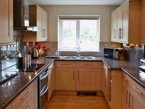 a kitchen with wooden cabinets and a sink and a window at The Old Butchers in Crantock