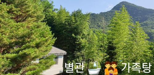 a house with a sign in front of some trees at 숲속온천호텔 in Changwon
